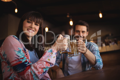 Portrait of happy couple toasting glasses of beer at counter