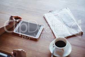 Hands of woman using digital tablet while having coffee