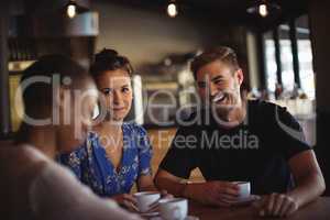 Happy friends interacting while having coffee