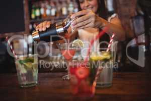 Pretty bartender pouring a cocktail drink in the glass