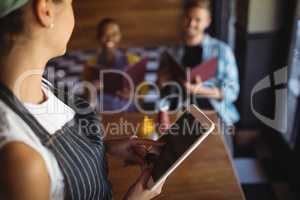 Waitress using digital tablet while taking order