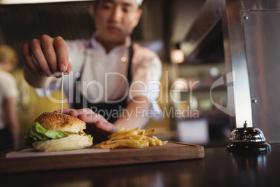 Chef placing tooth pick over burger at order station