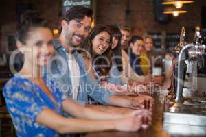 Smiling friends holding short glasses on counter in bar