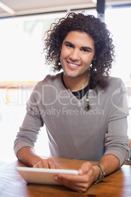 Smiling young man using tablet pc in restaurant