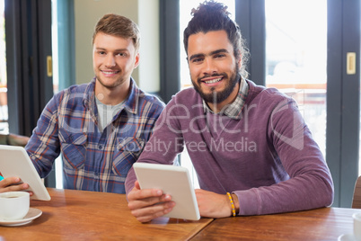 Male friends holding digital tablets in restaurant