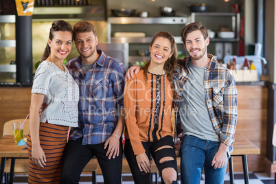 Portrait of friends leaning on table in restaurant