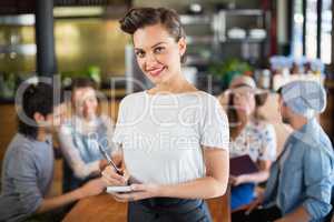 Portrait of waitress standing by customers in restaurant