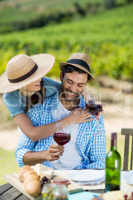Happy couple holding red wine glasses at table