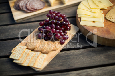 Red grapes with cookies and cheese on wooden table