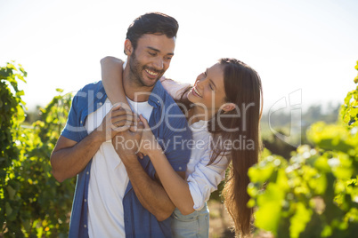 Cheerful couple embracing at vineyard during sunny day