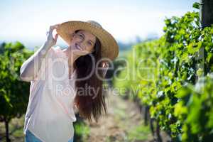 Smiling young woman standing at vineyard on sunny day
