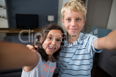 Siblings taking selfie in living room