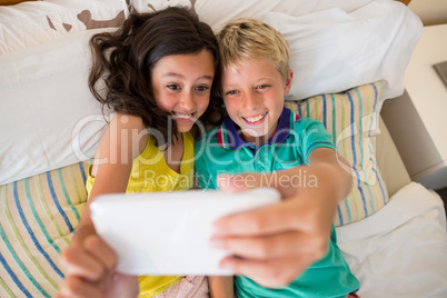 Siblings taking selfie on mobile phone in bedroom