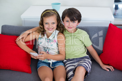 Sibling sitting on sofa with mobile phone in living room