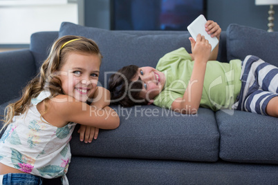 Smiling siblings with digital tablet looking at camera