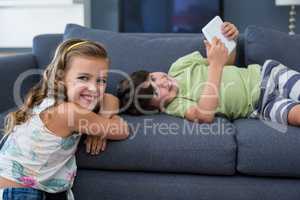 Smiling siblings with digital tablet looking at camera