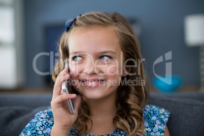 Happy girl talking on mobile phone in living room