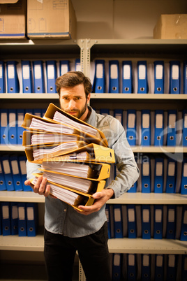 Worried businessman holding files in storage room