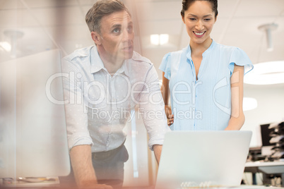 Businessman discussing with smiling female colleague at office