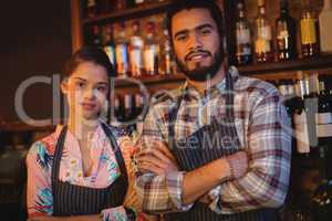 Portrait of waiter and waitress standing with arms crossed