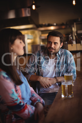 Couple interacting while having beer at counter