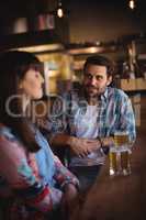 Couple interacting while having beer at counter