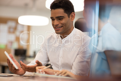 Smiling businessman discussing with female colleague on digital tablet