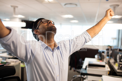Cheerful businessman with arms raised at office