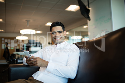 Portrait of businessman using mobile phone while sitting at office