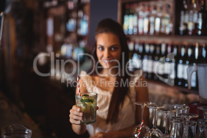 Portrait of female bar tender holding a glass of cocktail