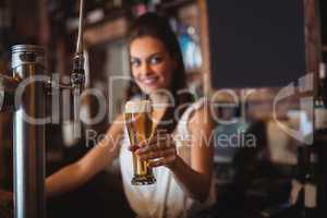 Female bar tender holding glass of beer