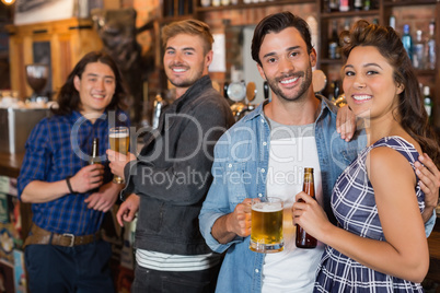 Portrait of friends with beer bottles and glasses in pub