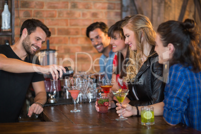 Smiling bartender serving drink for customers