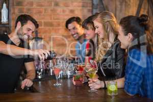 Smiling bartender serving drink for customers