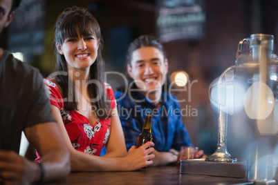 Portrait of smiling friends leaning at counter
