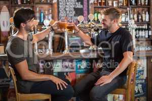 Happy male friends toasting beer mugs in bar