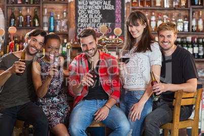 Portrait of friends holding beer bottles and wineglasses