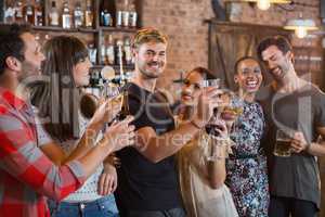 Young friends laughing together while holding drinks