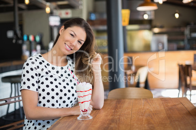Portrait of young woman sitting by drink on table