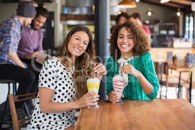 Portrait of happy female friends holding smoothies in restaurant