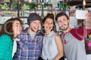 Friends making faces while talking selfie in restaurant