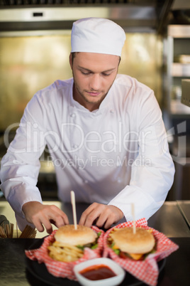 Serious male chef preparing burger in commercial kitchen