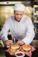 Serious male chef preparing burger in commercial kitchen