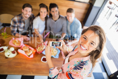 Portrait of woman photographing friends in restaurant