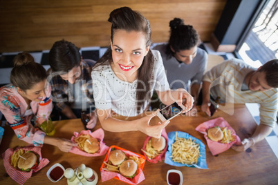 Young woman with friends photographing food in restaurant