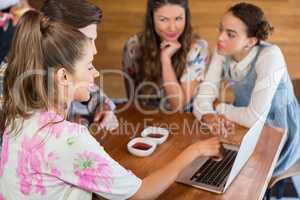 Friends discussing over laptop in restaurant