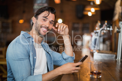 Young man using mobile while sitting at pub