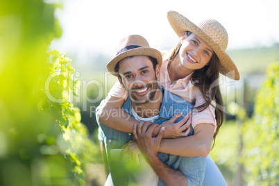 Portrait of smiling couple piggybacking at vineyard