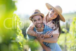Portrait of smiling couple piggybacking at vineyard