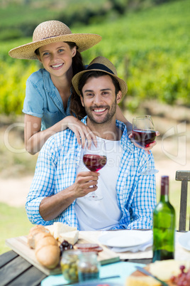 Portrait of happy couple holding red wine at table